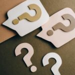 Artistic paper cutouts of question marks creating a conceptual design on a brown surface.